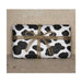 Clay & Colour Gift Wrap - Rectangular package wrapped in black and white cow print paper with a brown string bow on a beige background.